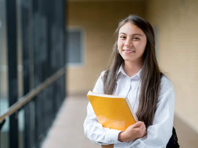 Student in a hallway holding notebooks